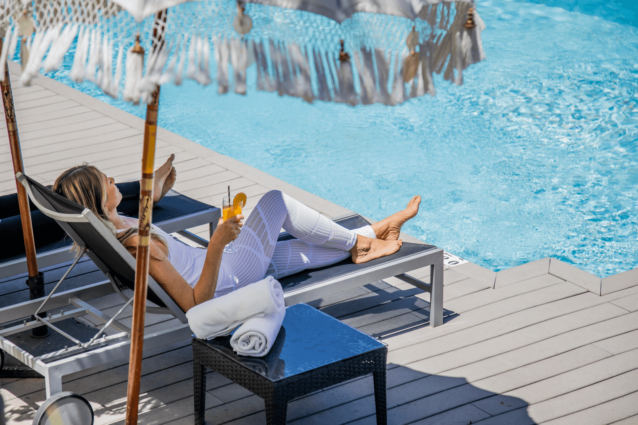 woman relaxing by pool with detox juice