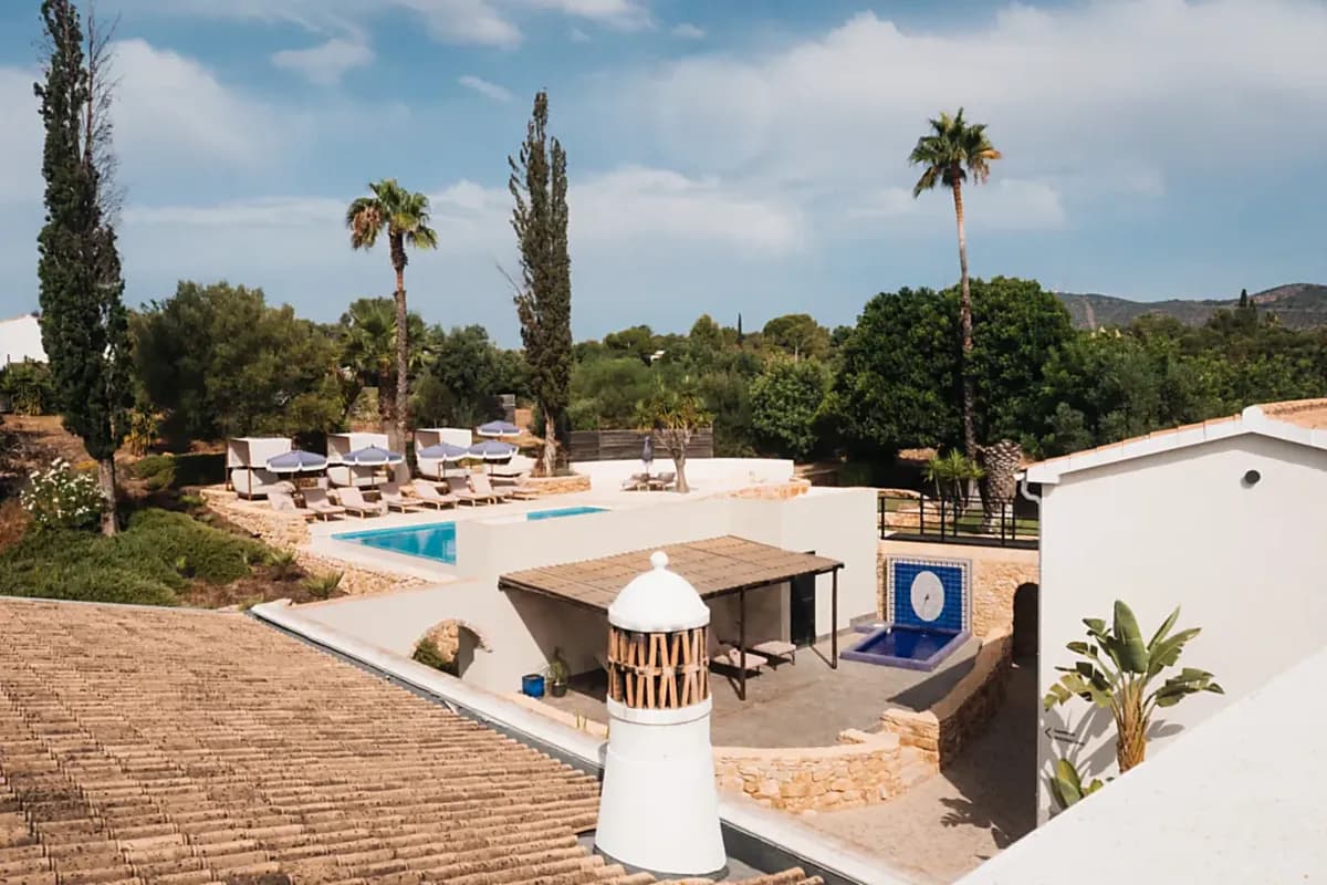 Pool and sun terrace at Shanti-Som Algarve among palm and cypress trees